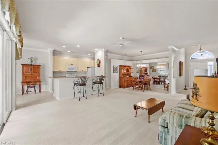 Living area with crown molding, ceiling fan and chandelier, light colored carpet, and recessed lighting