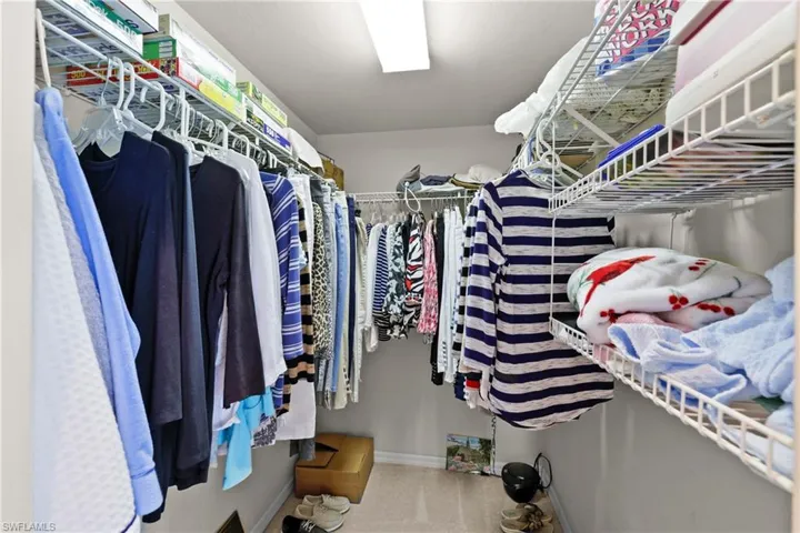 Spacious walk-in closet featuring carpet flooring. One of two closets in Primary.
