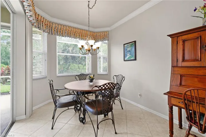 Breakfast room with lots of windows, light tile flooring, baseboards, a chandelier, and crown molding