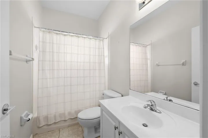 Full bathroom with toilet, vanity, shower / bathtub combination with curtain, and tile flooring