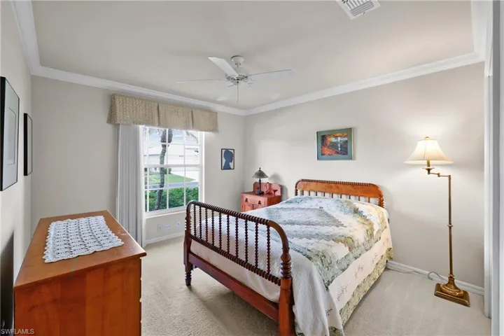 Carpeted bedroom featuring a ceiling fan, crown molding, baseboards, and window.