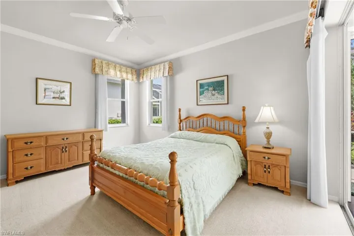 Primary Bedroom featuring crown molding, light carpet, baseboards, sliding glass doors and ceiling fan