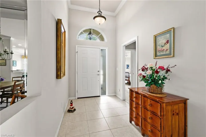 Foyer entrance featuring light tile floors, crown molding, and baseboards