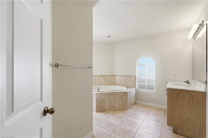 soaking tub with 1 vanity, shower and toilet to the right, and 1 vanity and linen closet to the left