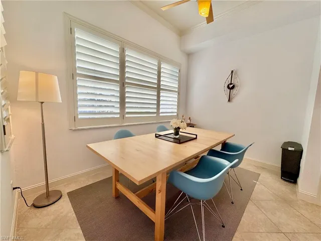 Tiled dining room with crown molding and ceiling fan