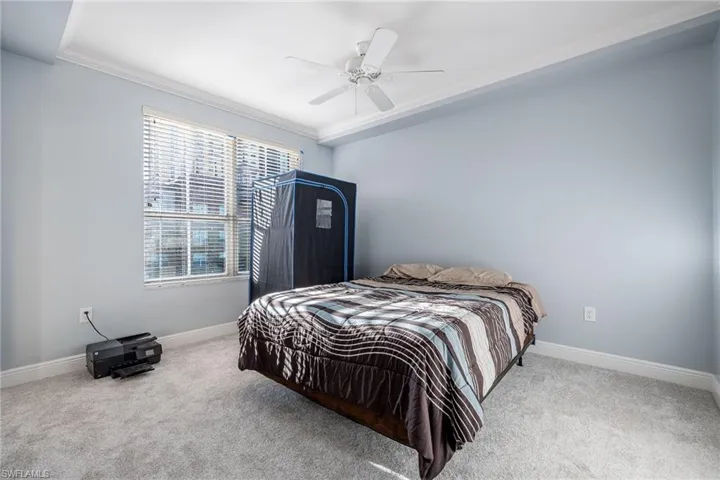 Bedroom with ornamental molding, carpet, and a ceiling fan