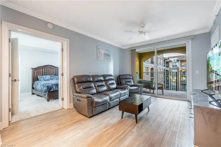 Living room featuring ornamental molding, light wood-style flooring, and ceiling fan