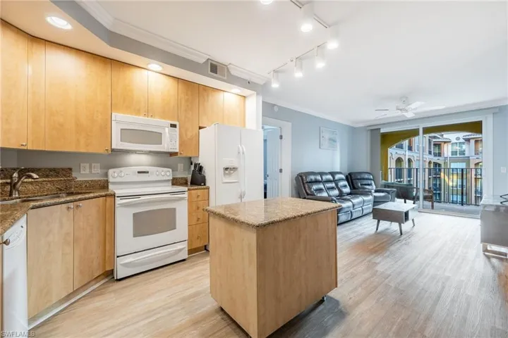 Kitchen featuring ornamental molding, white appliances, light brown cabinets, a ceiling fan, and a kitchen island