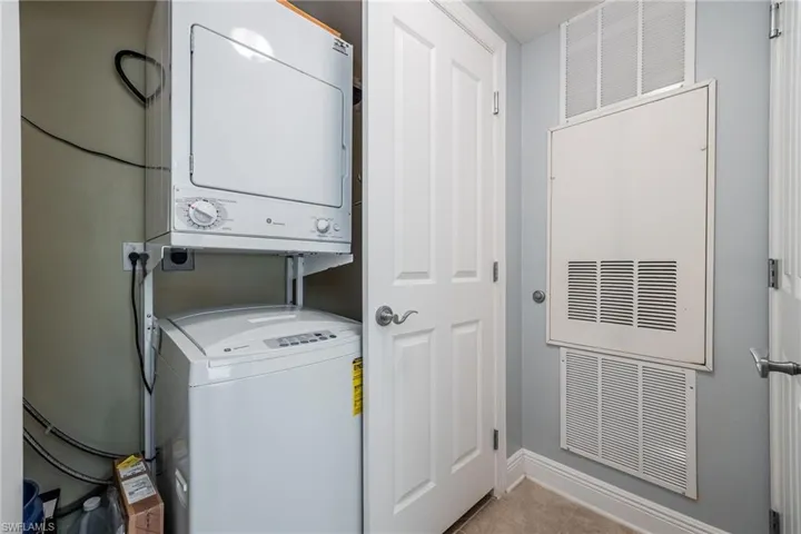 Laundry area with stacked washer and clothes dryer and baseboards