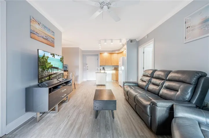 Living area with ornamental molding, light wood-style flooring, ceiling fan, and rail lighting