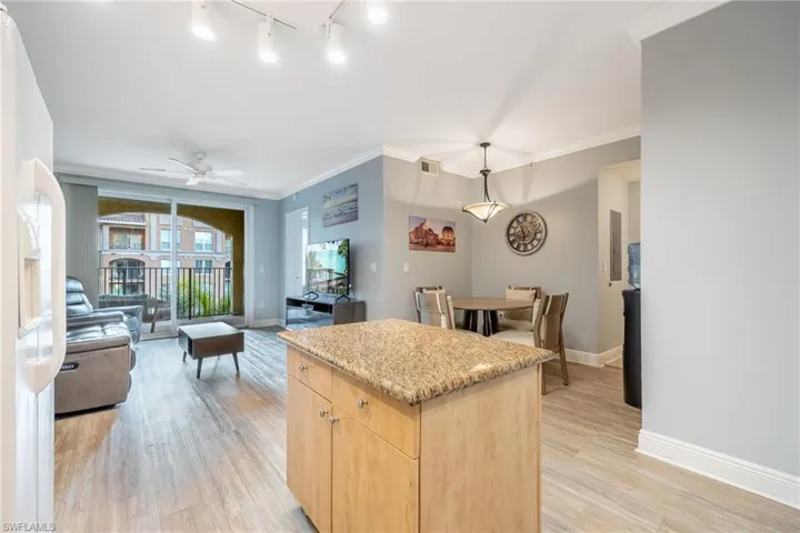 Kitchen with light brown cabinetry, white fridge with ice dispenser, a kitchen island, light wood-type flooring, and ornamental molding