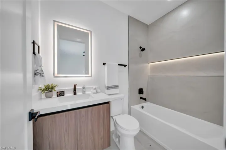Modern bathroom featuring a wood-finish vanity with a white countertop and integrated sink