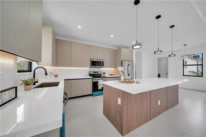 Modern kitchen featuring an expansive island with a white countertop and wood-finish cabinetry