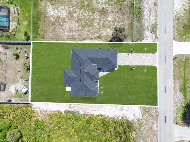 Newly constructed residence with a dark shingle roof and a spacious, manicured lawn