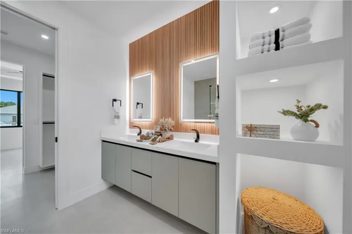 Dual vanity with matte black fixtures, back-lit mirrors, and a slatted wood-finish accent wall