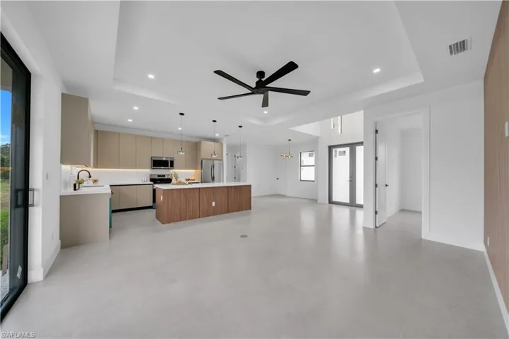 Open-concept living space featuring a modern kitchen with an expansive island, stainless steel appliances, and contemporary cabinetry