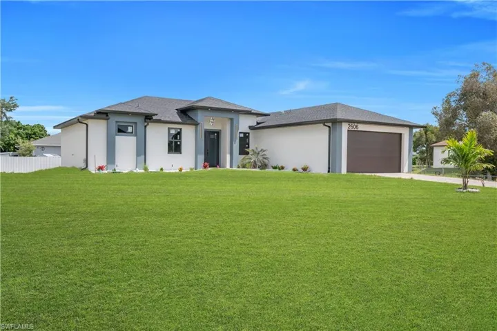 Modern stucco exterior with contrasting trim, a dark asphalt shingle roof, dark-framed windows, and an integrated two-car garage with a dark wood-finish door