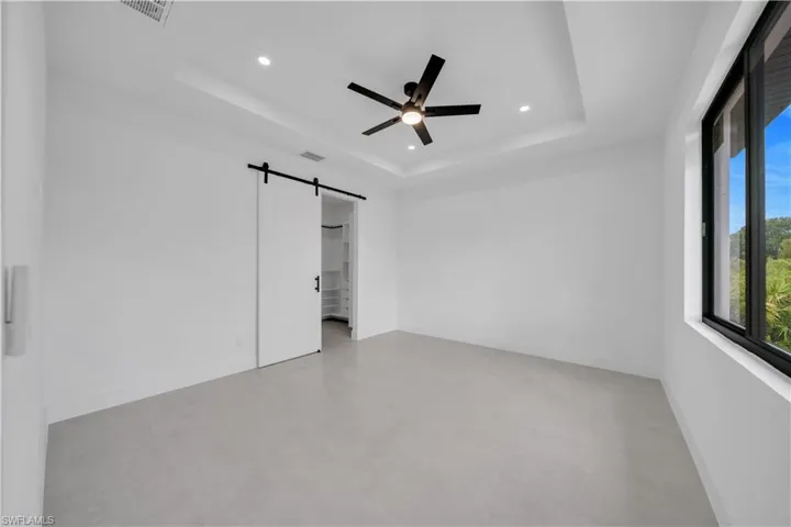Spacious room featuring light-colored flooring, white walls, and a tray ceiling with recessed lighting