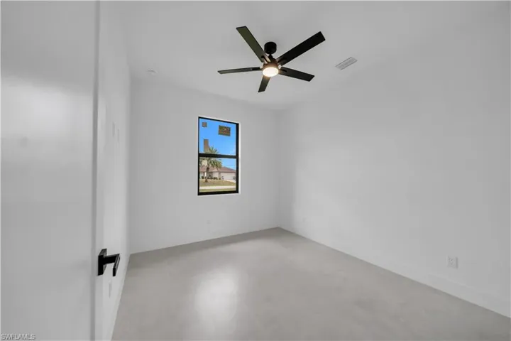 Interior room featuring a black ceiling fan with integrated lighting, a dark-framed window, and light-toned flooring