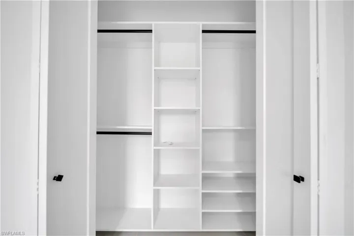Integrated white custom closet system featuring multiple shelving units and black hanging rods