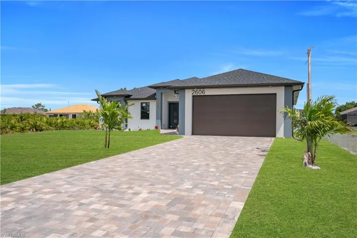 Contemporary single-story residence featuring a dark asphalt shingle roof and a paver driveway