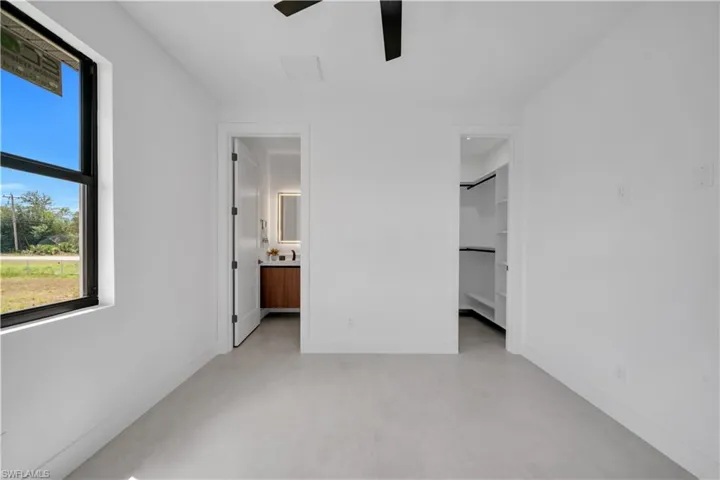Spacious room featuring light-toned flooring, white walls, and a ceiling fan
