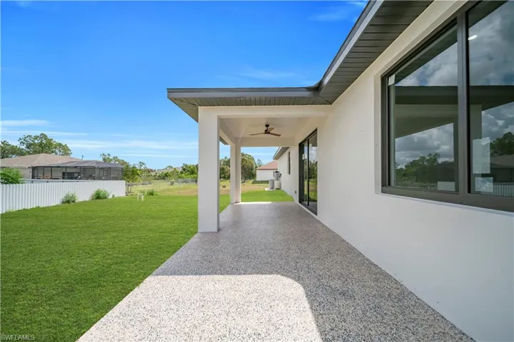 Expansive covered patio with a speckled aggregate finish and ceiling fan