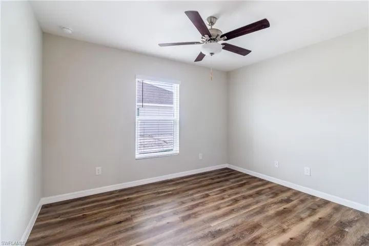 Spare room with dark wood-type flooring and ceiling fan