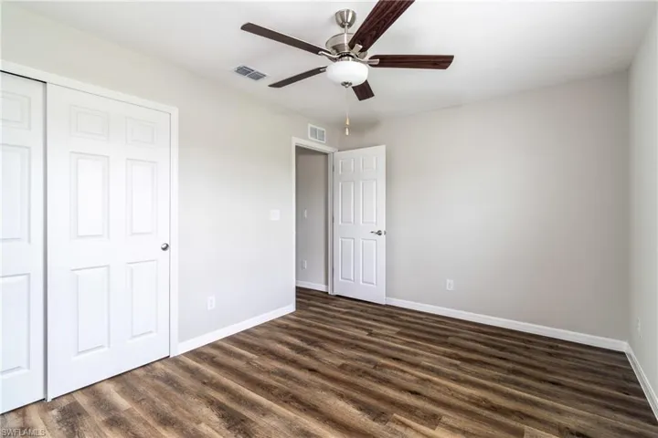 Unfurnished bedroom featuring dark wood-type flooring, ceiling fan, and a closet