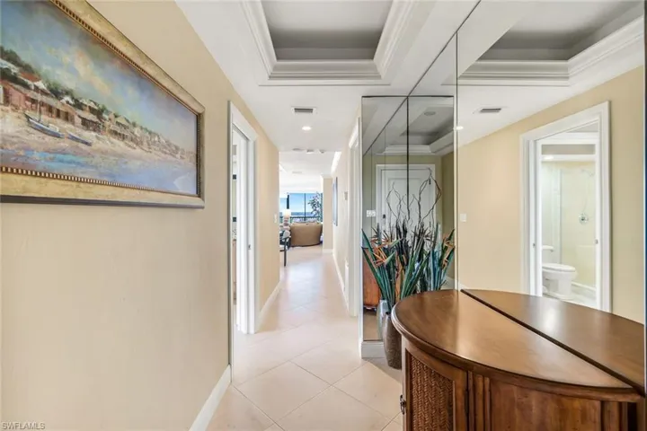 Corridor featuring a tray ceiling and light tile patterned flooring