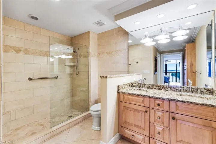 Bathroom featuring double vanity, a walk in shower, ornamental molding, recessed lighting, and light tile patterned floors