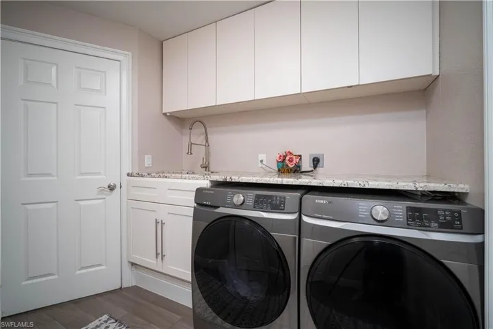 Laundry area featuring sink, dark hardwood / wood-style flooring, cabinets, and independent washer and dryer