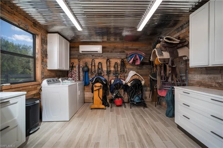 Laundry room with wood walls, light hardwood / wood-style flooring, and cabinets