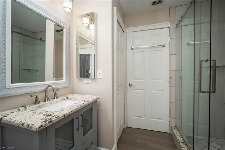 Bathroom with vanity, a shower with shower door, and hardwood / wood-style flooring