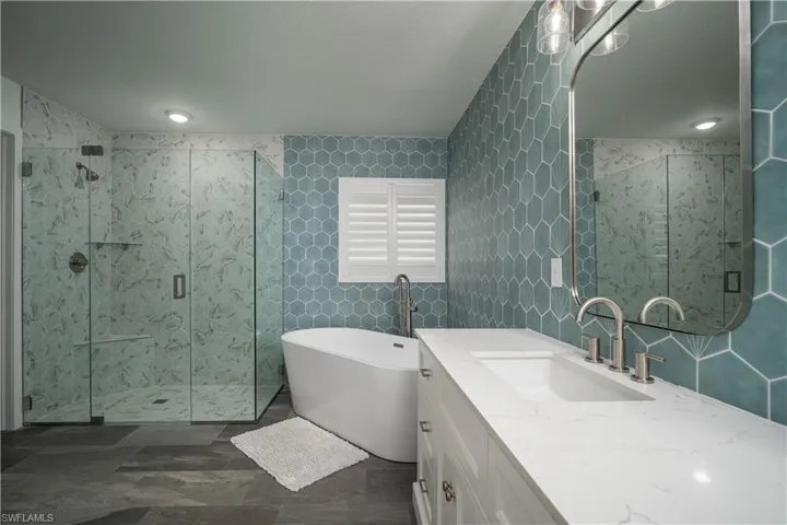Bathroom featuring a textured ceiling, plus walk in shower, vanity, and tile walls