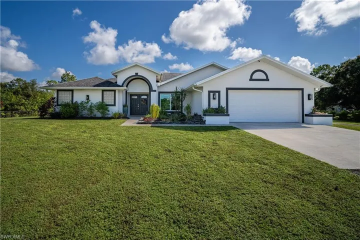 Single story home with a garage and a front lawn