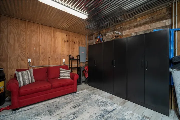 Living room featuring electric panel, wood walls, and light wood-type flooring