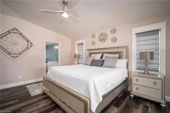 Bedroom featuring connected bathroom, ceiling fan, dark wood-type flooring, and lofted ceiling