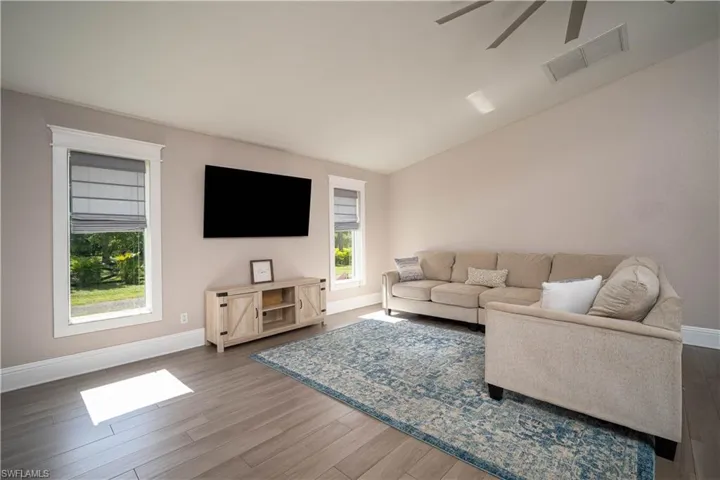 Living room with ceiling fan, hardwood / wood-style floors, and vaulted ceiling