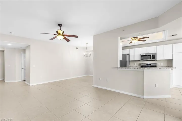 Kitchen with ceiling fan, white cabinetry, stainless steel appliances, suspended lighting, and open floor plan