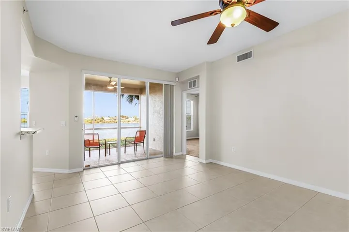 Spare room with ceiling fan, a water view, and light tile patterned flooring