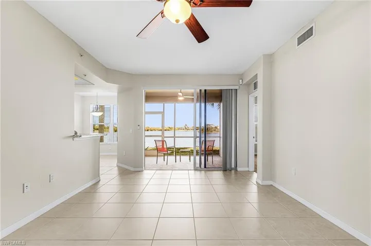 Empty room with ceiling fan, a water view, and light tile patterned floors