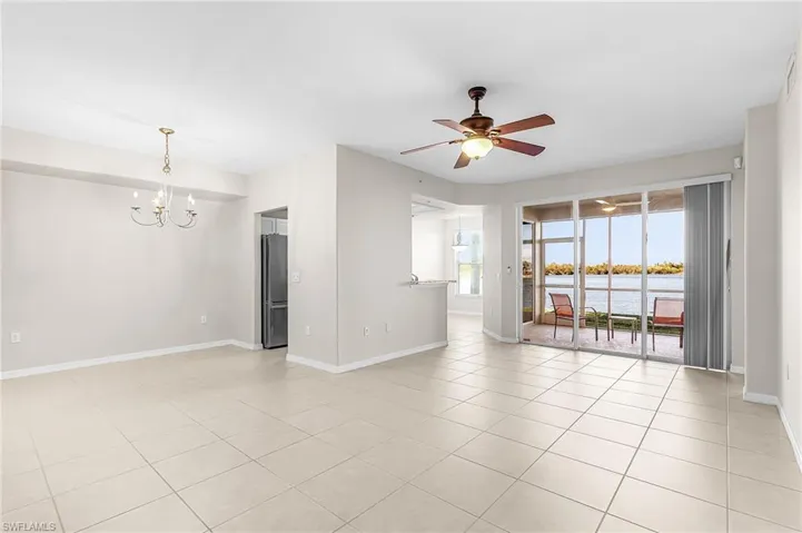 Spare room featuring a chandelier, a ceiling fan, a water view, and light tile patterned flooring