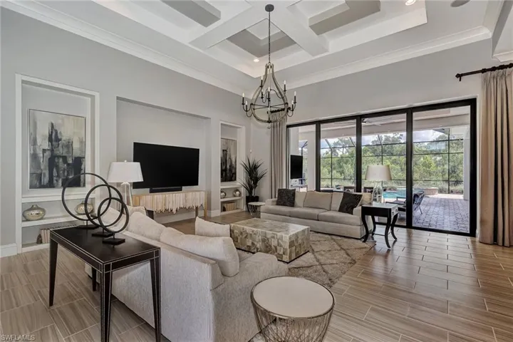 Living room featuring a notable chandelier, ornamental molding, coffered ceiling, and a towering ceiling