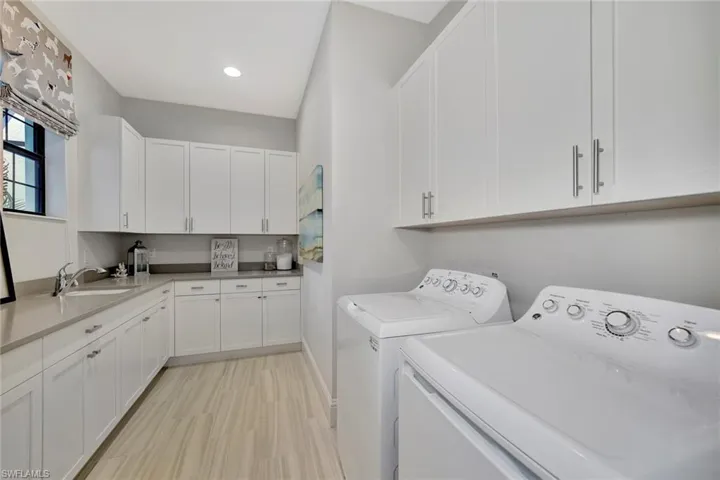 Laundry area featuring sink, independent washer and dryer, and cabinets