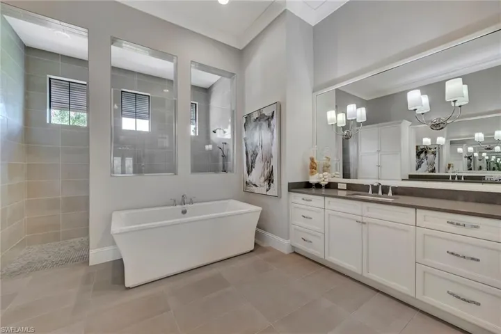 Bathroom with tile floors, a bathtub, oversized vanity, and an inviting chandelier