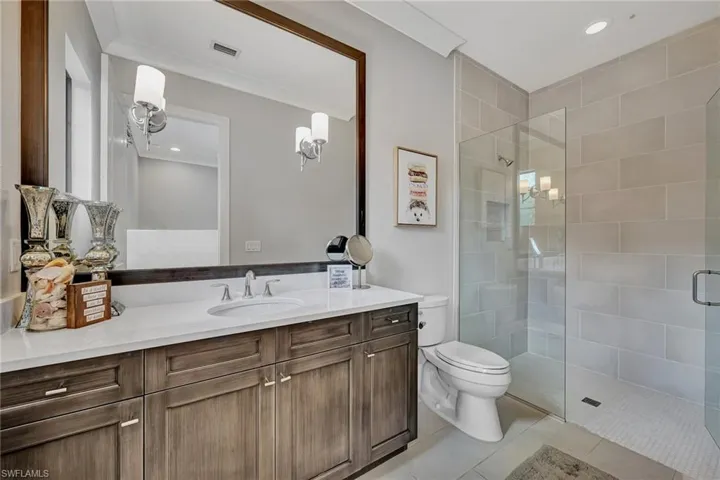 Bathroom with tile floors, toilet, walk in shower, and oversized vanity