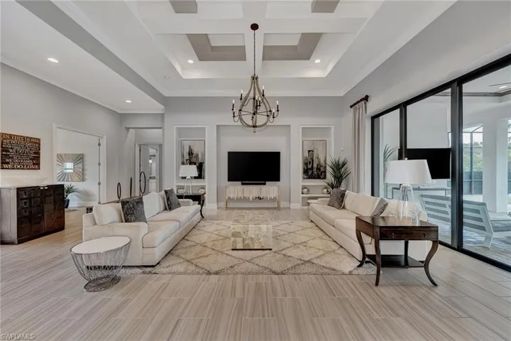 Living room with a chandelier, ornamental molding, and coffered ceiling