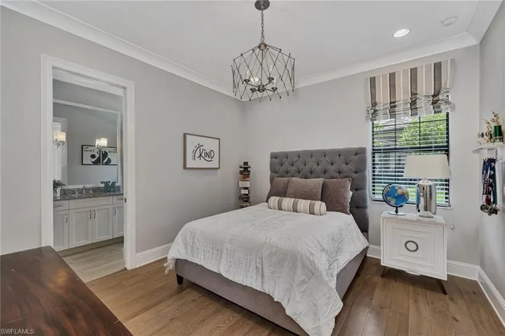 Bedroom featuring crown molding, hardwood / wood-style flooring, a chandelier, sink, and ensuite bathroom