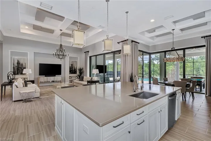 Kitchen featuring a center island with sink, white cabinetry, and coffered ceiling
